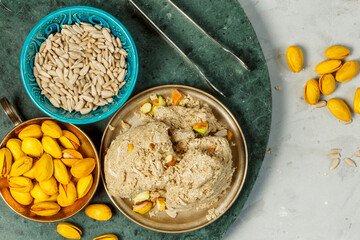 Halva, sunflower seeds, pistachios on a green marble stand. Close-up, top view