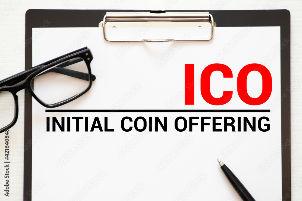 Poster a notebook with business notes initial coin offering ico with office tools on blue background.
