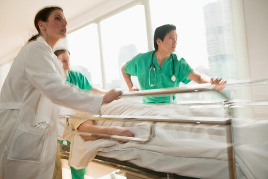 Healthcare workers pushing gurney in emergency room
