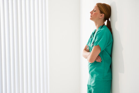 Tired doctor leaning against wall