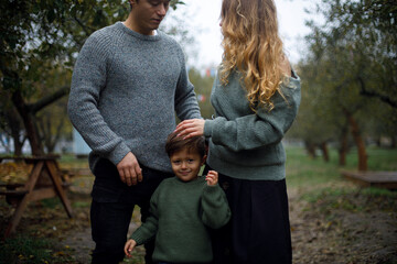 young curly woman with a manicure stroking the child on the head. cheerful sly boy stands in the...