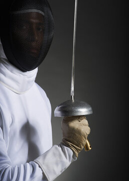 Studio portrait of fencer holding fencing foil