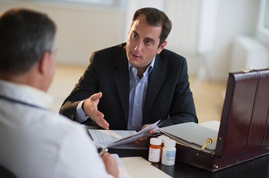 USA, New Jersey, Jersey City, Medical sales representative talking with doctor in office