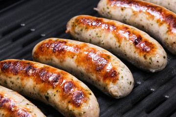 Delicious german sausages on the barbecue electro grill. Tasty sausages sizzling on a portable electric grilling on a summer picnic, close up view. 4k resolution video.
