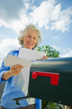 USA, New Jersey, Jersey City, Senior woman checking mail at mailbox