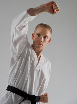 Young man performing karate stance on white background