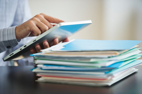 USA, New Jersey, Jersey City, Businessman using digital tablet by paperwork