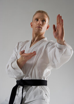 Young man performing karate stance on white background