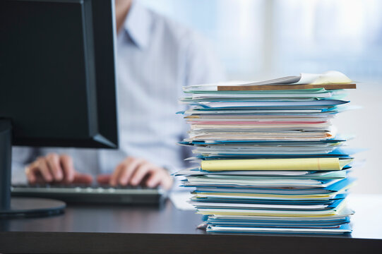USA, New Jersey, Jersey City, Paperwork on desk by businessman using computer
