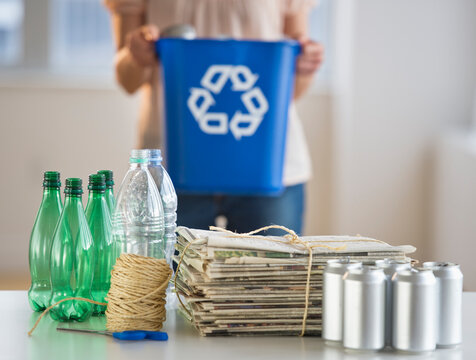 Woman recycling plastic bottles, cans and newspapers