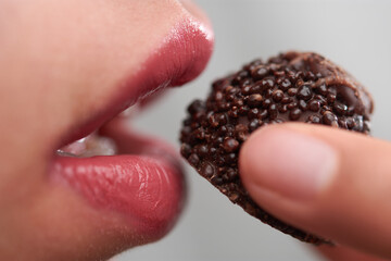 girl eating a chocolate with a texture, closeup of the mouth