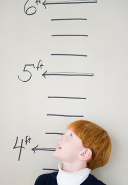 Boy (8-9) measuring height against chart