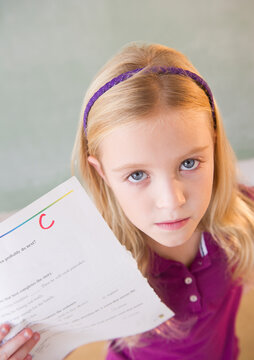 USA, New Jersey, Jersey City, Sad schoolgirl (8-9) showing test results with C-grade