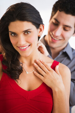 Young couple, man fastening woman's necklace