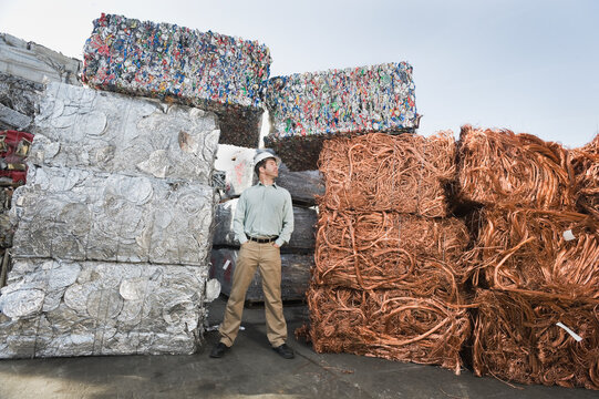 Worker standing beside stacks of recycled material