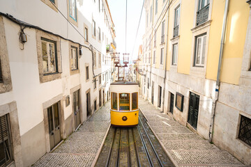 Trams in Lisbon city. Famous retro yellow funicular tram on narrow streets of Lisbon old town on a sunny summer day. Tourist attraction