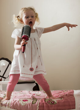 Young girl singing on her bed