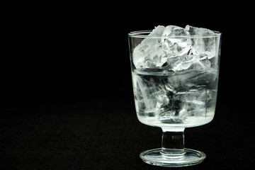 Half-filled glass with ice on a black background