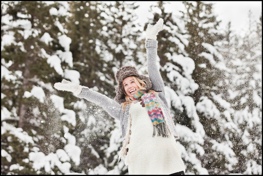 USA, Utah, Salt Lake City, young woman in winter clothing throwing snow in air