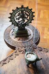 Shiva Nataraja figure stands on an Afghan prayer table. Out of focus in the foreground an incense stick. 