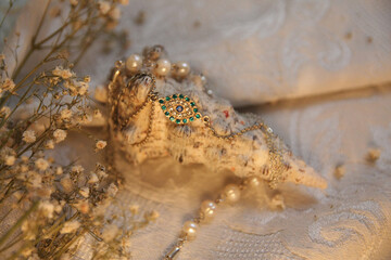 Ocean white shell with a blue eye-shaped jewelry bracelet on a vintage fabric with dried flowers and natural pearl beads.