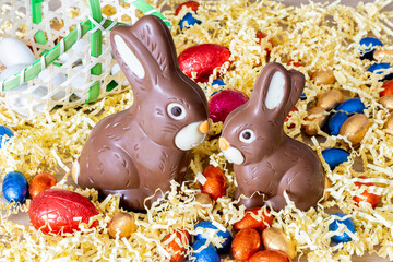 Pâques. Deux lapins en chocolat au lait sur de la paille. Paniers avec œufs de pâques