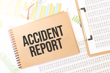 Business up graph on a sheet of craft colour Notepad with ACCIDENT REPORT sign. Notepad on desk with financial documentation