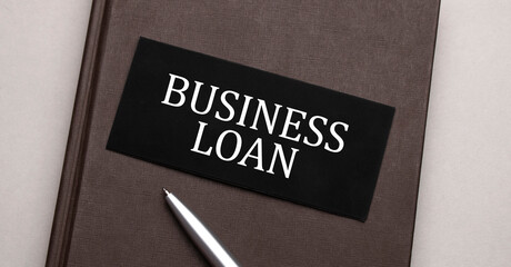 BUSINESS LOAN sign written on the black sticker on the brown notepad. Tax concept