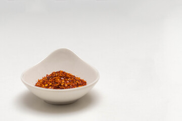 ceramic container with cayenne pepper flakes with copy space on white background food concept