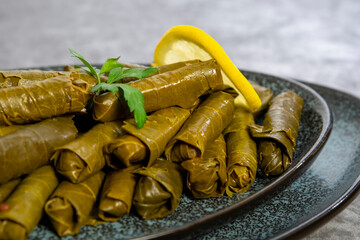 Plate with delicious, stuffed grape leaves with parsley and lemons called Dolma , made from vines with rice, meat and spices.