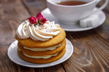 Sponge cake with cream, decorated with small flowers and a cup of tea.