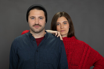 beautiful long-haired brunette girl leaned on shoulder of Handsome unshaven guy in knitted cap...