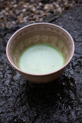 Matcha tea from Japan in a small tea cup. Photographed on a dark stone. 