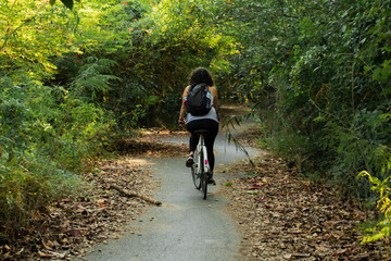 Woman riding a bike on the park full of trees 