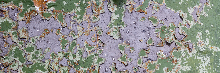 Peeling paint on the wall. Panorama of a concrete wall with old cracked flaking paint. Weathered rough painted surface with patterns of cracks and peeling. Wide panoramic texture for grunge background