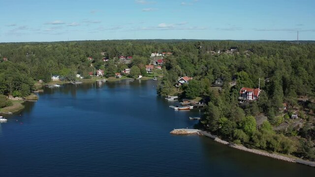 Picturesque quiet bay in Archipelago in Scandinavia, Northern Europe. Residential area with sailing boats. Summer day aerial flying over water and stone islands with boats, houses, villas, jetty, dock