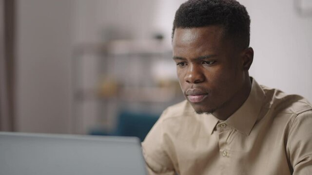 black male programmer is viewing on laptop display concentrated, working from home, remote job and freelance