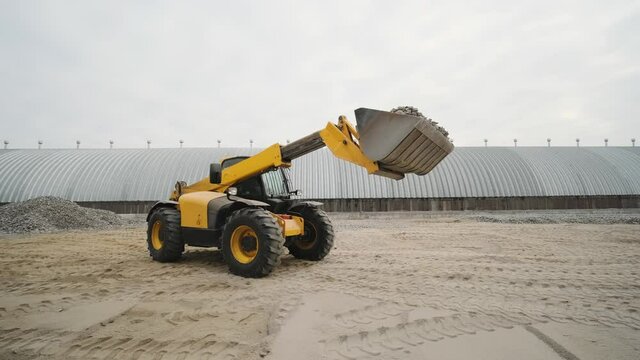 Tractor moves rubble to truck. Excavator-loader rakes rubble from pile at construction site and loads dump truck. Clearing site