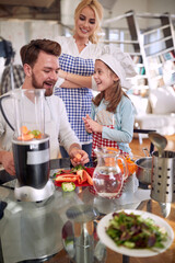 A young happy family enjoy preparing a meal at home together. Family, home, kitchen