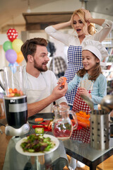 A young mother is worried that her husband and little daughter will destroy a meal they are preparing at home. Family, home, kitchen