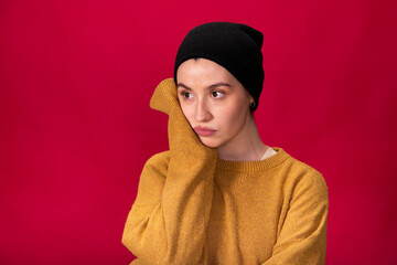 brunette hipster girl in black knitted cap and mustard sweater thinking about meaning of life on...