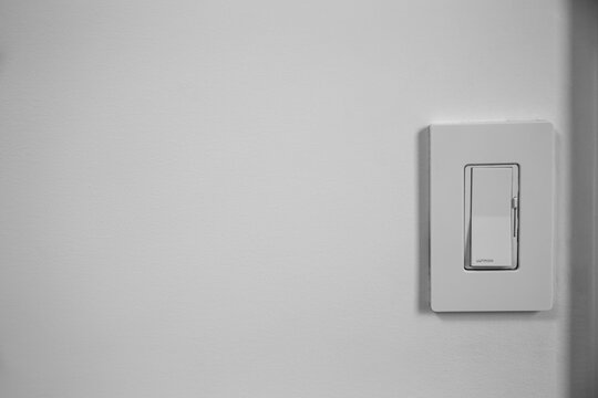 Single light switch dimmer on a white wall with space for text