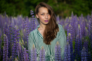 Gorgeous beautiful girl in striped summer dress with magnificent dark hair posing on blooming...