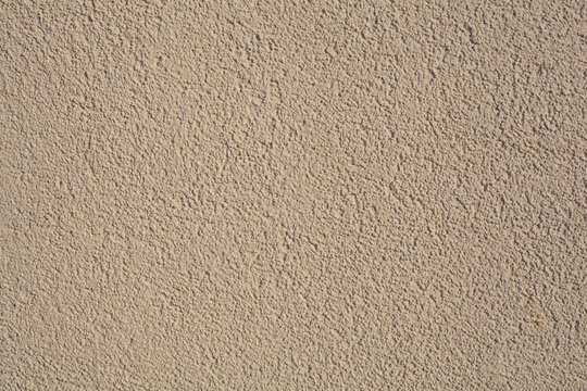 Simple brown background texture in the form of a rough granular coating with putty or plaster on a flat surface