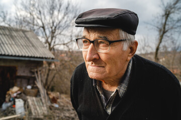 Portrait of senior caucasian man in nature standing in spring or autumn day - close up of cheerful male pensioner farmer standing in rural nature on farm looking to the side - real people concept