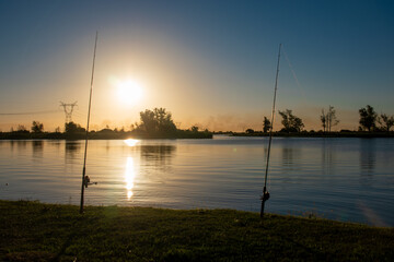 Obraz premium two fishing rods in beautiful river of Argentina at sunset with a beautiful landscape