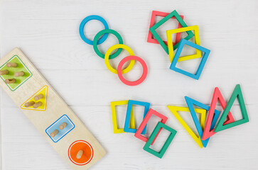 Multicolored wooden toys, blocks on white background. Trendy puzzle toys. Geometric shapes: square, circle, triangle, rectangle. Educational toys for kindergarten, preschool or daycare. Close up