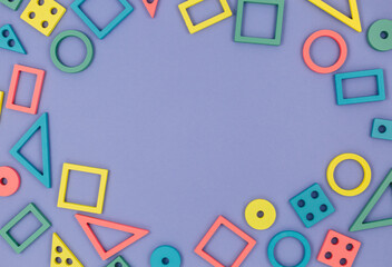 Multicolored wooden toys, blocks on violet background. Trendy puzzle toys. Geometric shapes: square, circle, triangle, rectangle. Educational toys for kindergarten, preschool or daycare. Close up