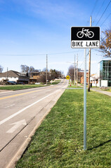 Bike lane road sign on green grass pathway, safety for bicycle with arrow direction marking on asphalt route. Outdoor sport activity for cyclist, active transportation for healthy lifestyle in summer.