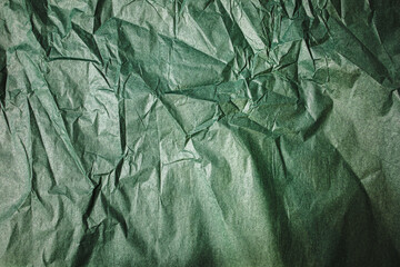 Abstract dark green wrinkled paper background with natural light.